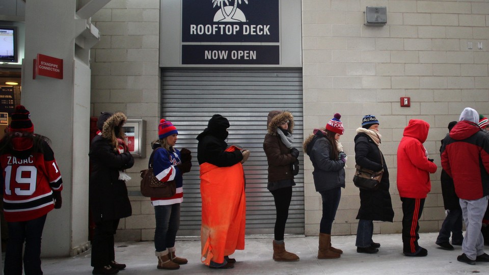 Women wait in a long line for a restroom at a sports stadium.