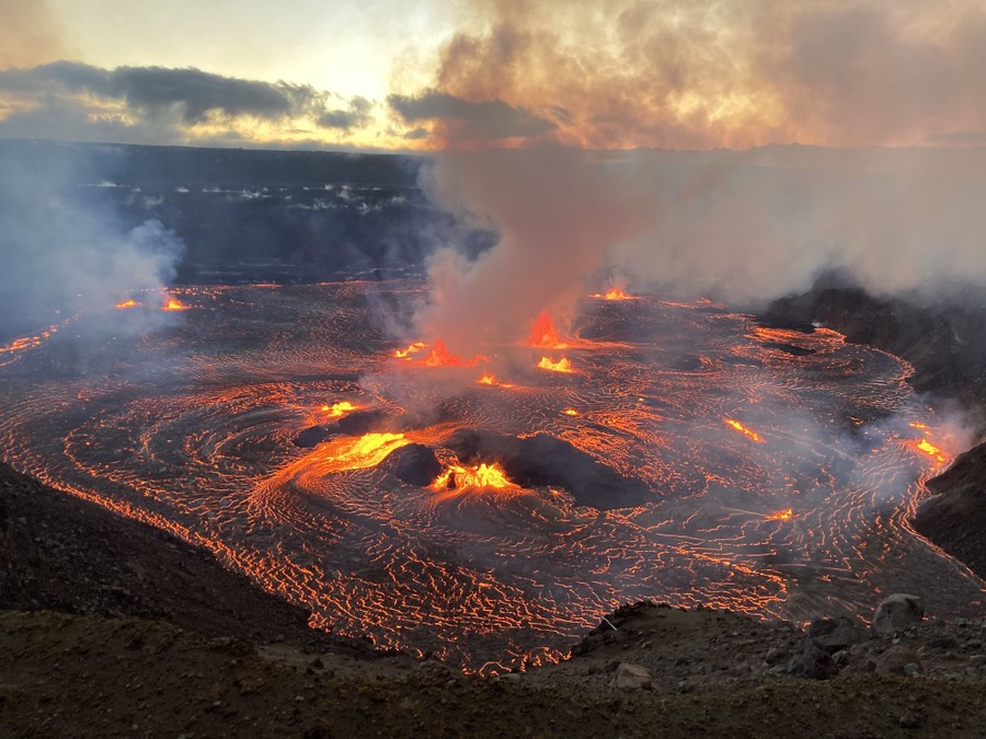 A lake of molten lava sputters and sends up plumes of gas and steam.