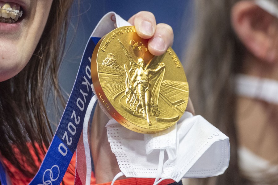A swimmer holds up her gold medal.
