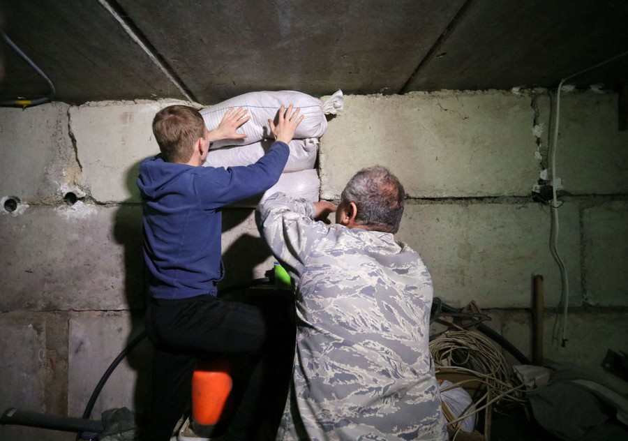 A teenager and man place sandbags against a basement wall.