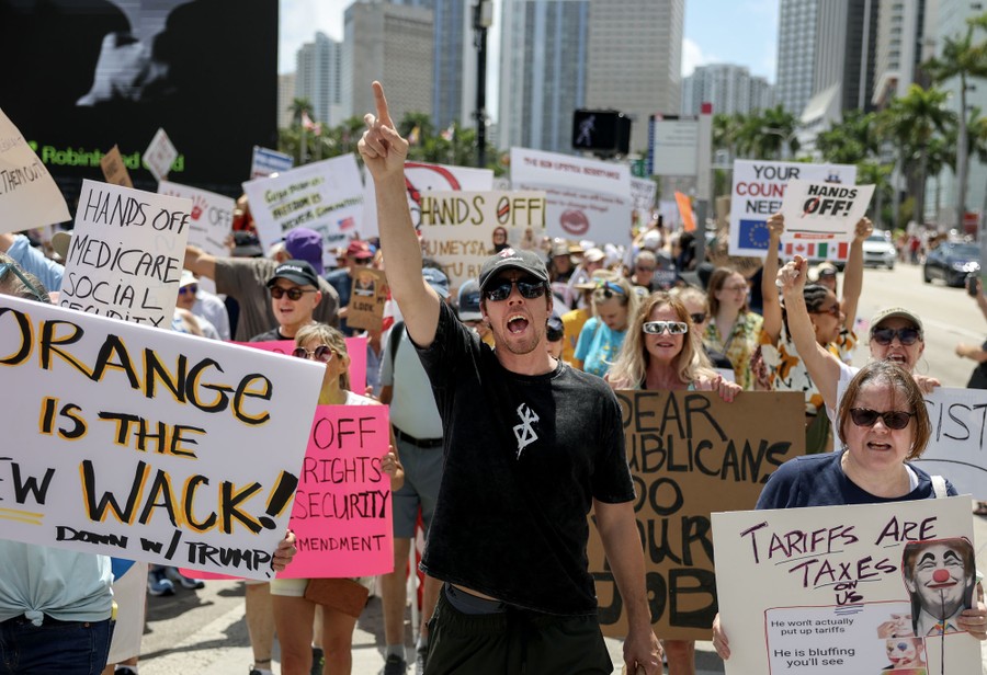Protesters carrying anti-Trump signs march in a street in Miami.
