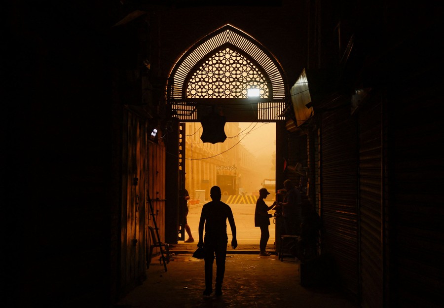 A view looking out of an ornate door, looking toward an orange, dusty street scene outside.
