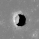 The opening to a lunar pit forms a black crescent on a gray landscape.