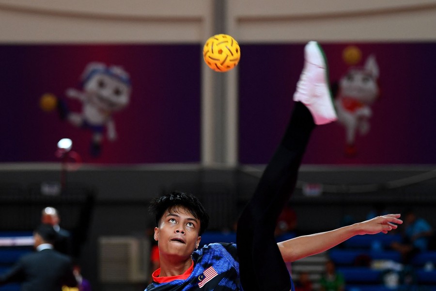 An athlete kicks a ball high above their head.