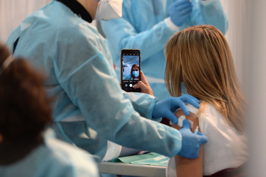 A person takes a selfie as she is vaccinated.