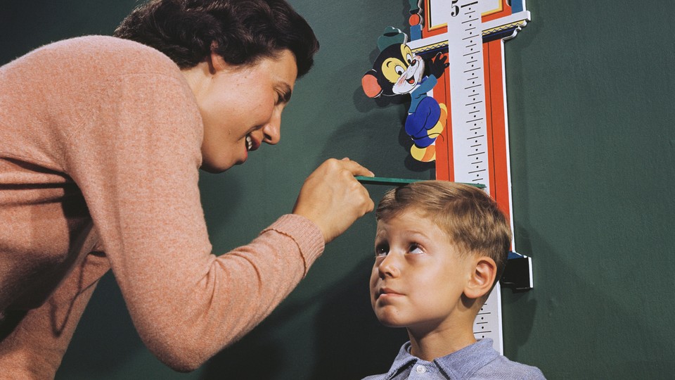 A mother measuring the height of her child.