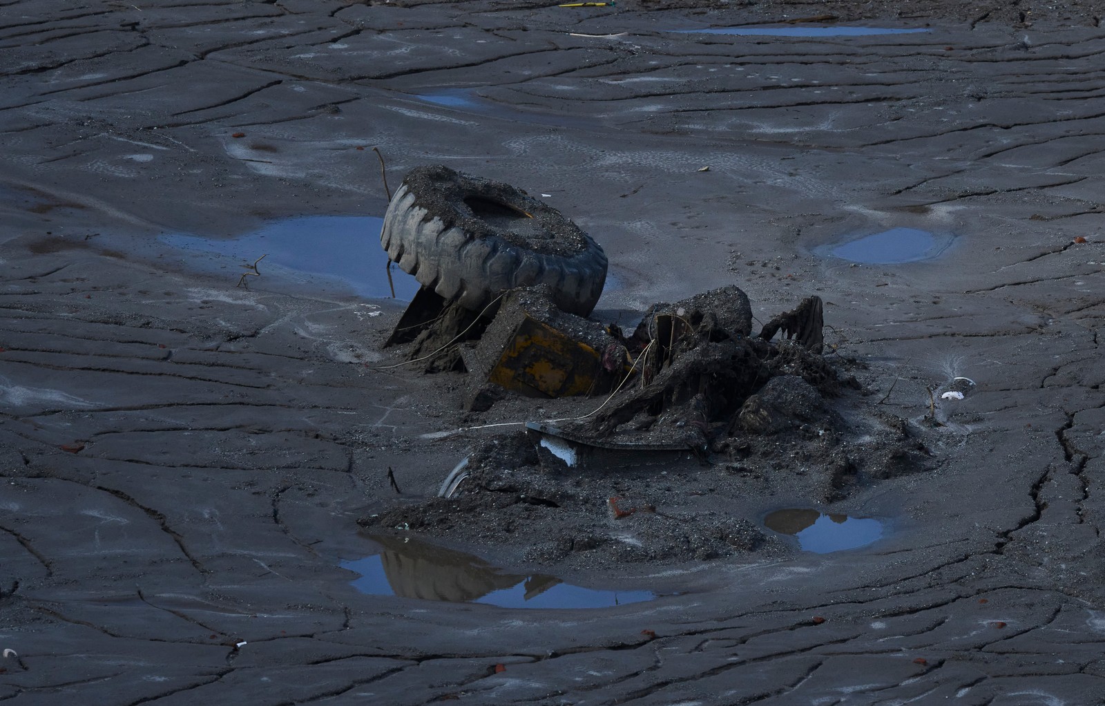 A partially-buried truck is seen in thick mud.