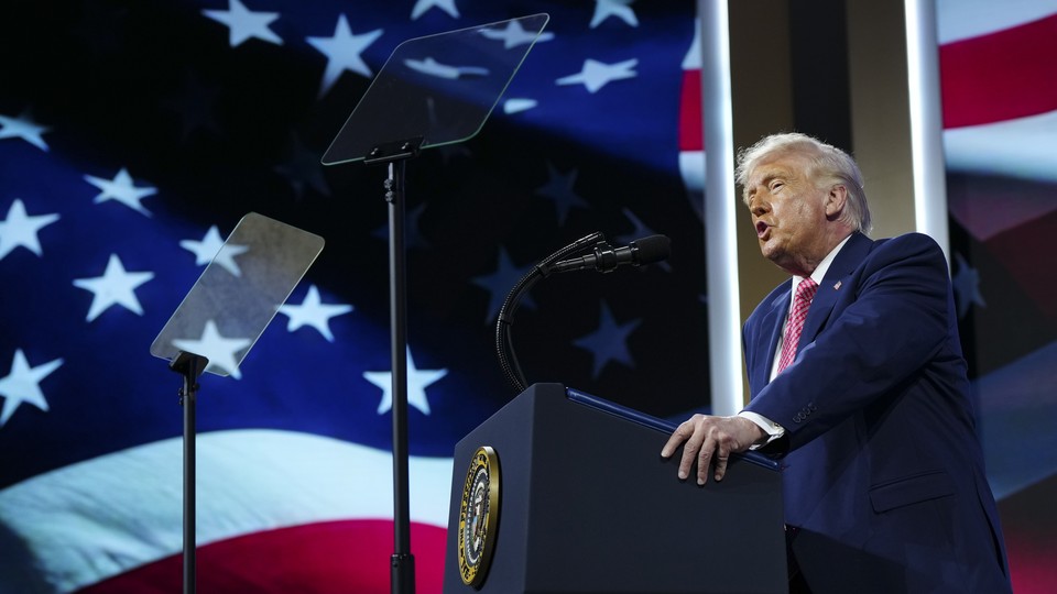 An image of President Trump speaking from a podium in front of a large American flag backdrop
