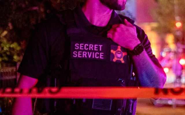 Man in a Secret Service vest at night time