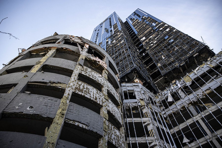A view from the ground up at the exterior of a tall office building heavily damaged by a missile attack.