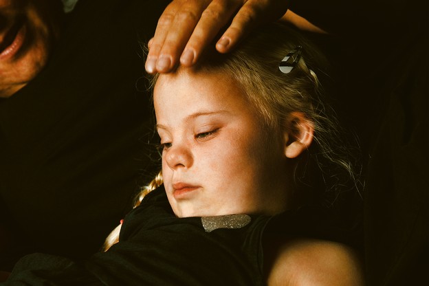 parent with hand on head of young girl