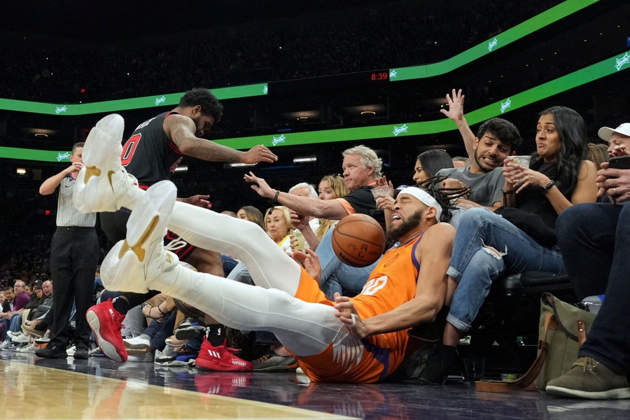 A basketball player falls into the first row of fans during a game.