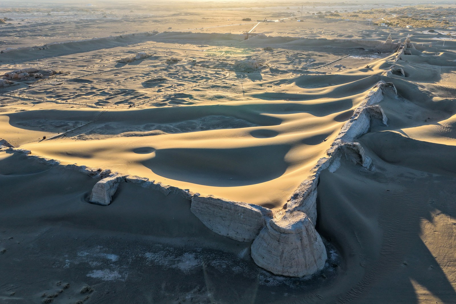 Sand dunes sweep over the site of an ancient ruin in a Chinese desert.