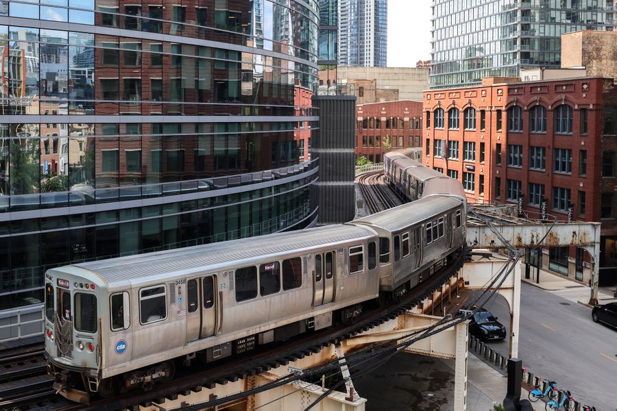 A train rides on elevated railway tracks among buildings.