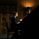 John Ratcliffe sits at a table in a low-lit, wood-paneled room.