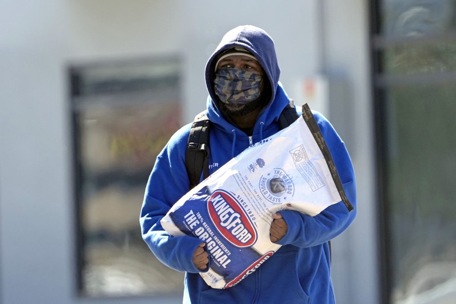 A man carries a bag of charcoal in cold weather.
