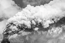 Fotografía en blanco y negro de humo saliendo de una chimenea.