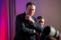 Elon Musk looks down while standing in front of House Speaker Mike Johnson