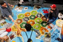 Three young men play the German board game Settlers of Catan