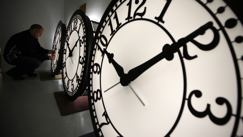 Close-up view of three clocks; a man is examining the far-left one