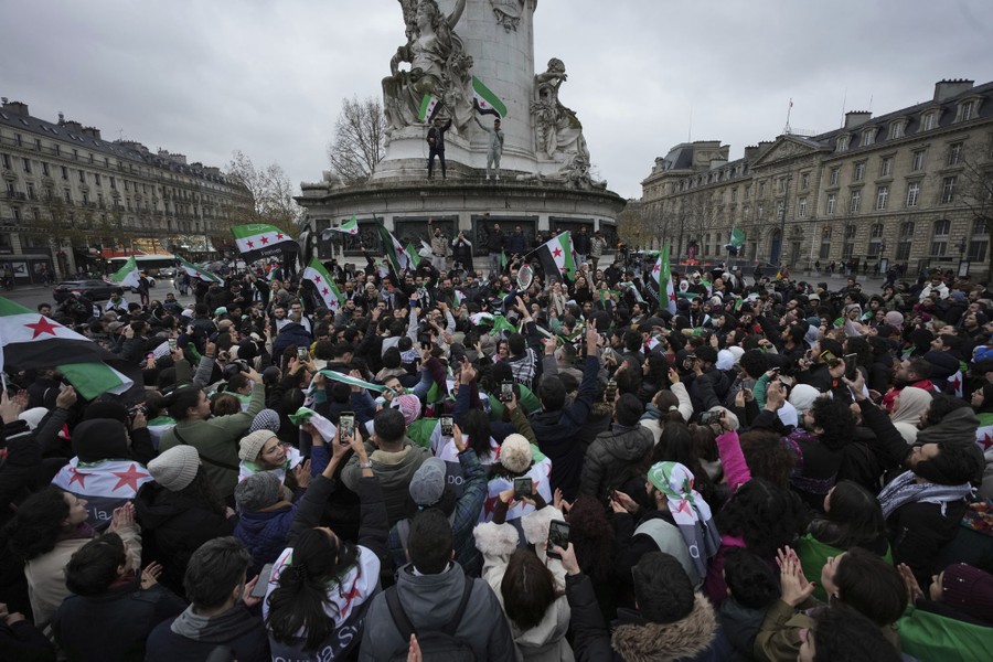 A crowd gathers around a monument, celebrating.