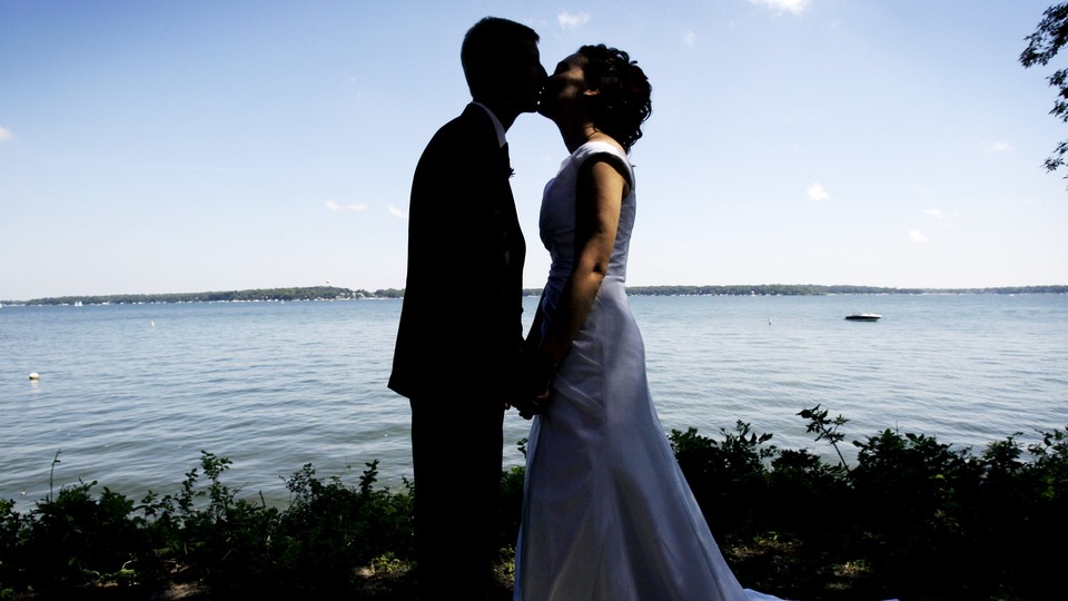 A couple kisses following their wedding ceremony by a lake in Milford, Iowa.