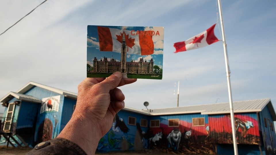 A photo of a Canadian postcard being held up next to a Canadian flag
