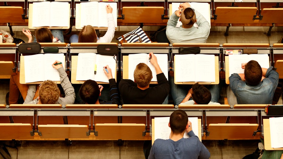 An overhead shot of students with open notebooks on desks in a lecture hall