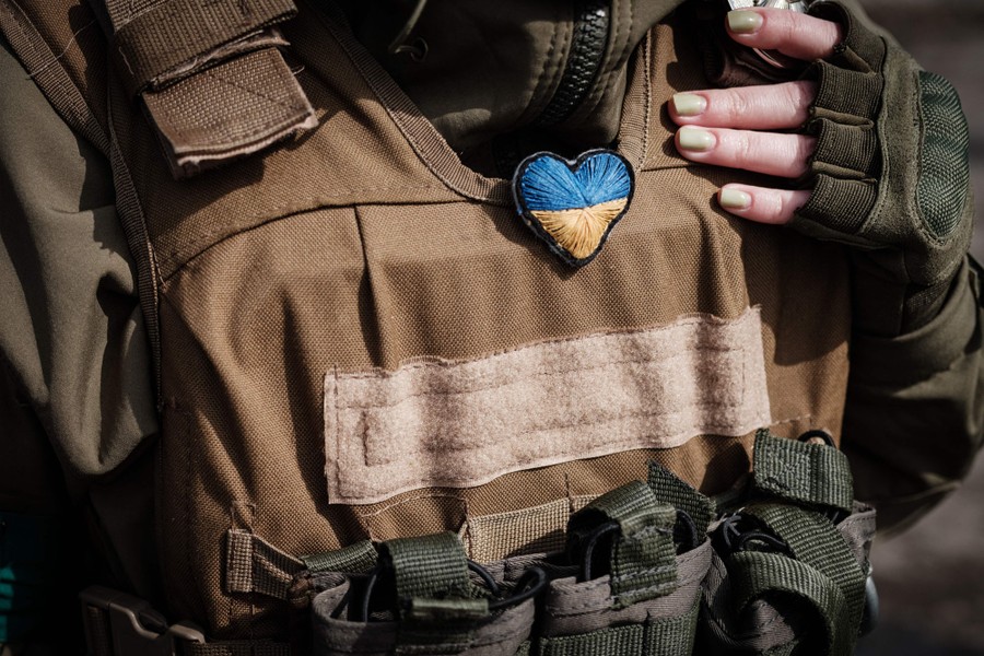 A small handmade blue-and-yellow heart hangs from the uniform of a soldier.
