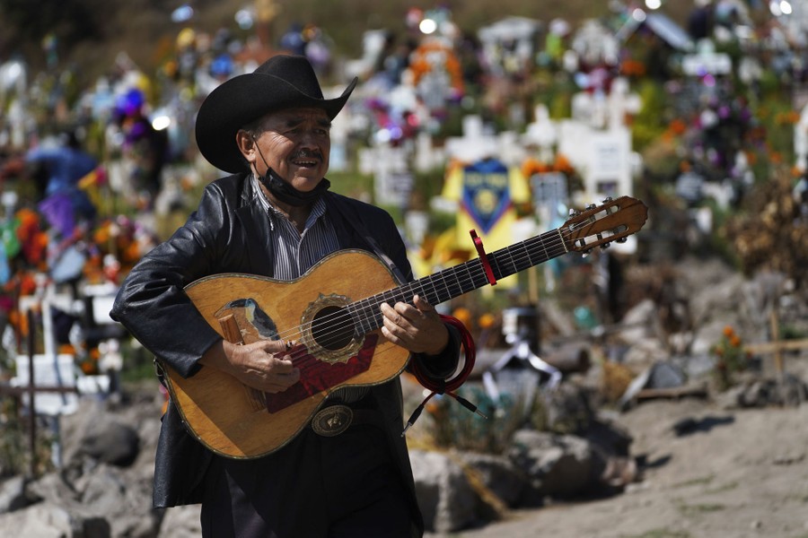 A man plays a guitar in a cemetery.