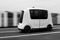 A driverless car on a road, moving against a blurry background