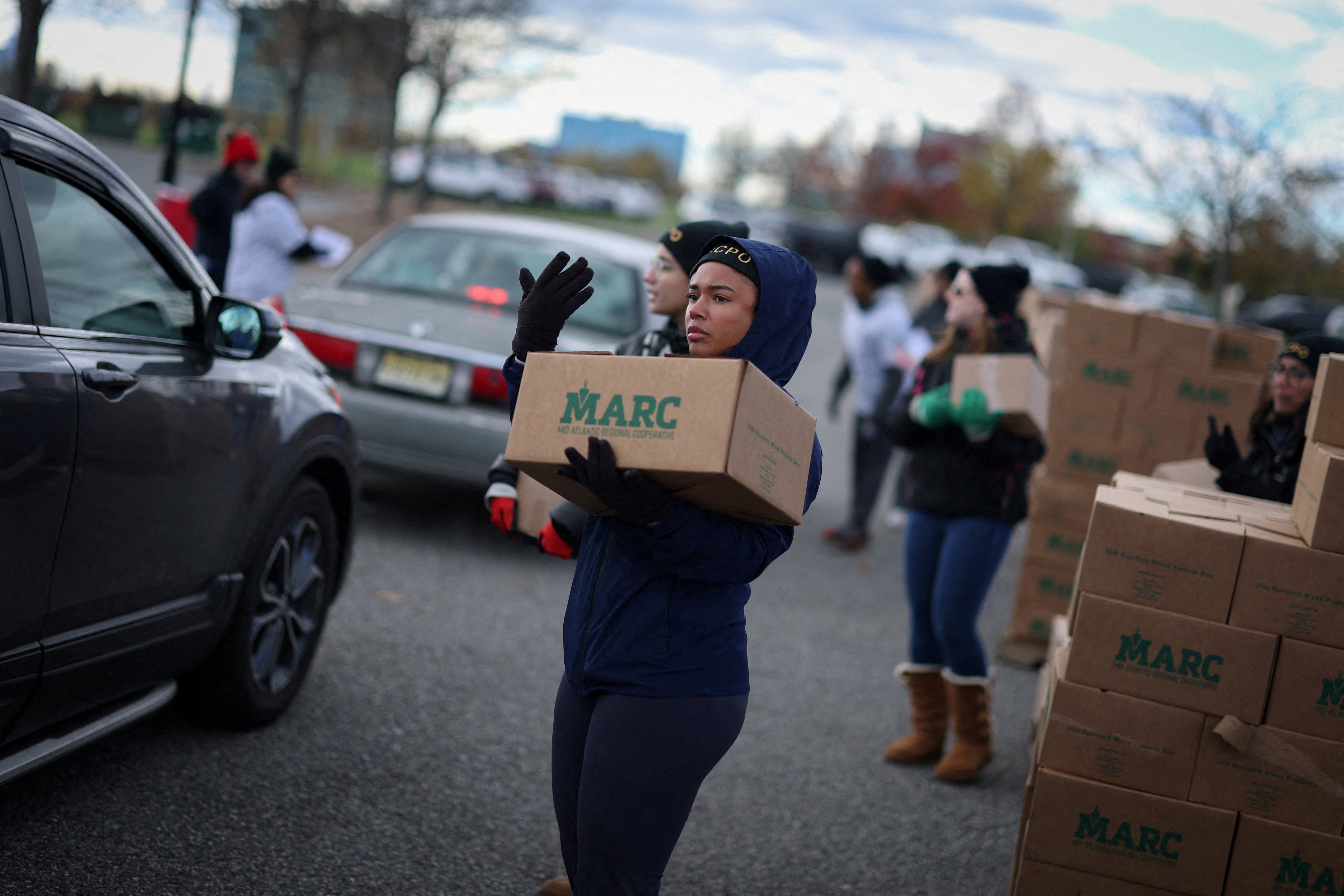 Volunteers load boxes of food into cars during a food bank event.