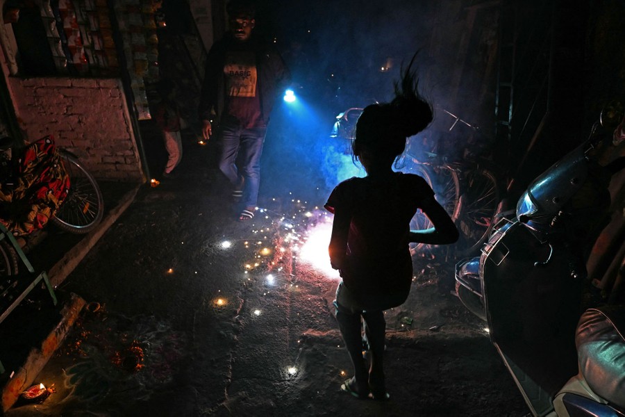 People set off small fireworks in a street.
