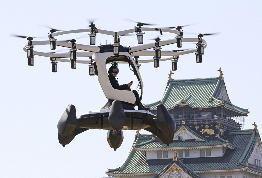 A person flies a small drone-like aircraft near a Japanese castle.