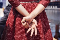 A woman in a red dress with her hands crossed behind her back