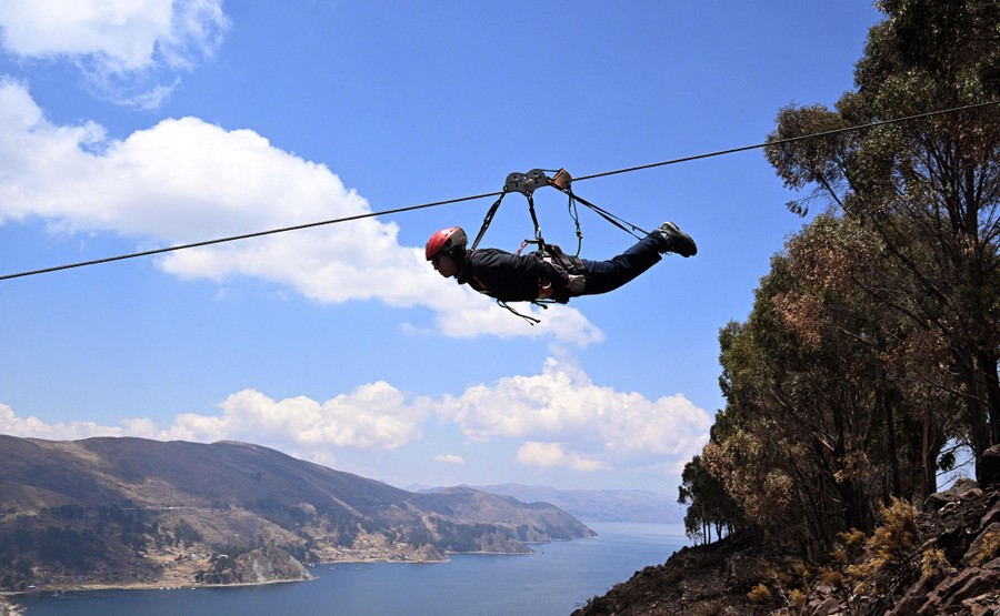 A person lies prone, in a harness suspended from a zip line.