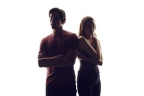 A boy and girl stand back to back. 