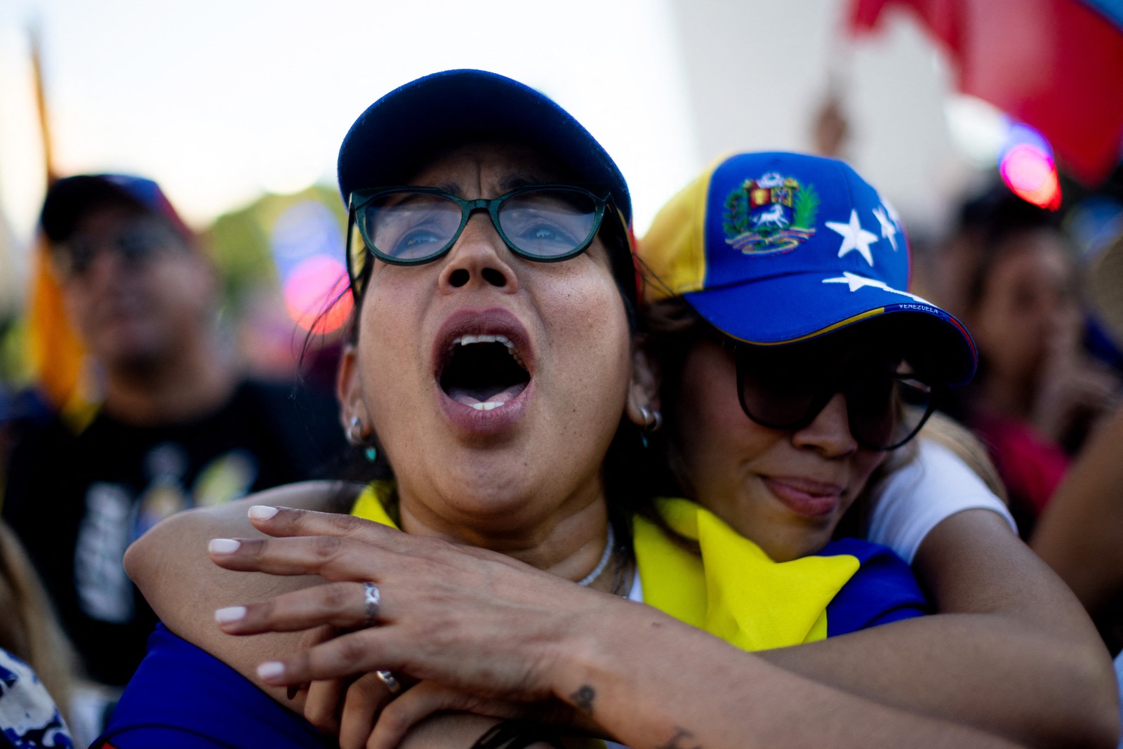 Two people embrace, as they celebrate, surrounded by others in a public square.