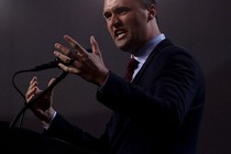 A photo of Charlie Kirk speaking at a mic with a bright orb of light above his head