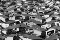 A warped black and white photograph of rows of houses in a neighborhood