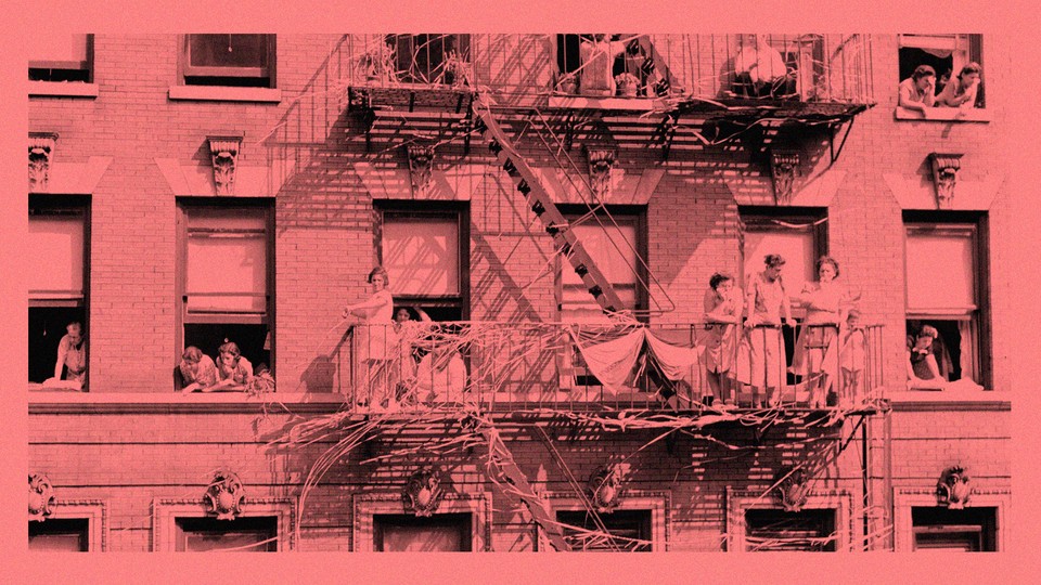 An antique photo of families and children looking out the windows of an apartment building and standing on a fire escape