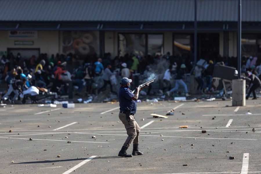 A police officer fires rubber bullets at rioters.