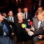 Siv Jensen walks out surrounded by reporters with microphones.