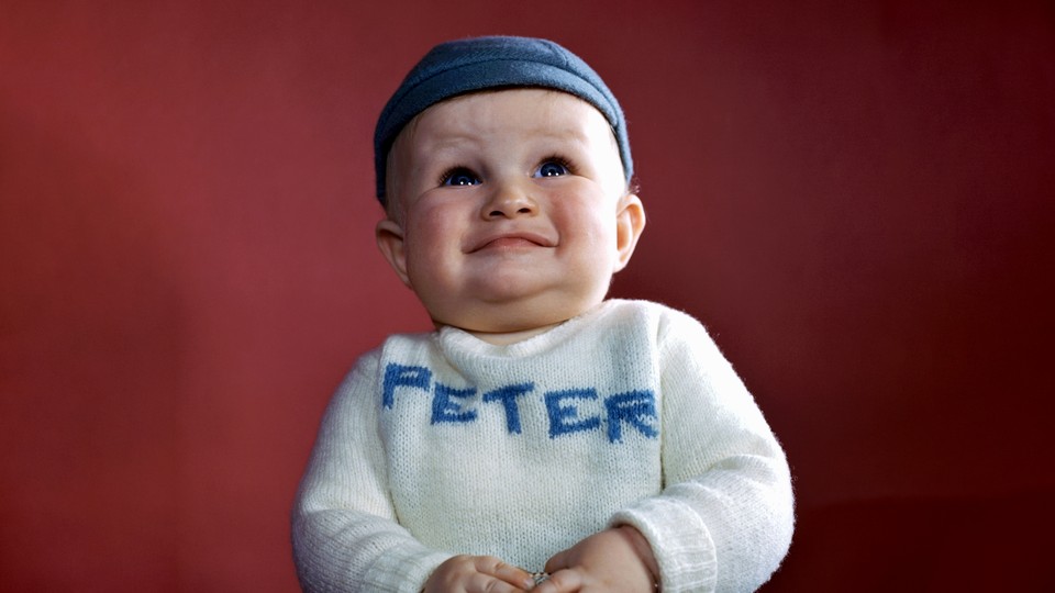 A photograph of a baby wearing a sweater that says "Peter" on it