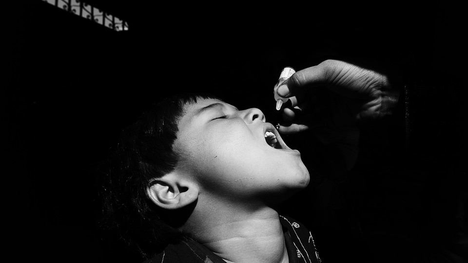 A child opens his mouth to receive the oral polio vaccine