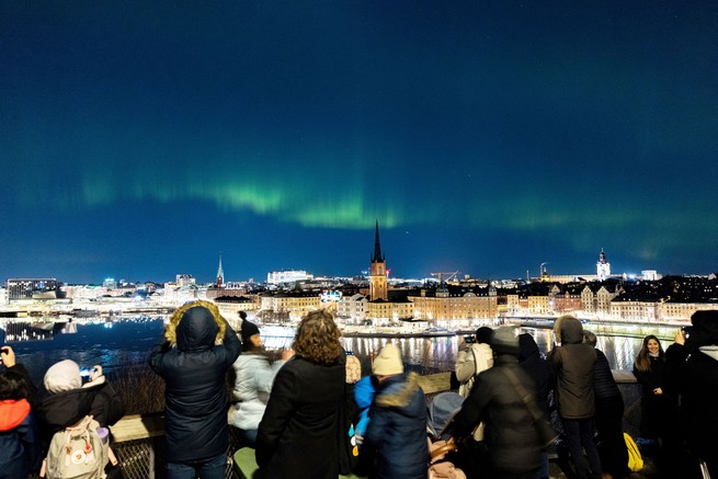 Les gens regardent les aurores boréales au-dessus du centre de Stockholm, en Suède, le 27 février 2023. 