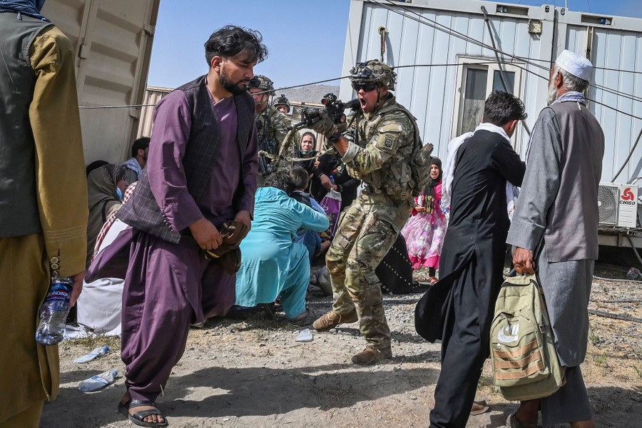 A U.S. soldier brandishes his weapon amid a crowd of Afghan people.