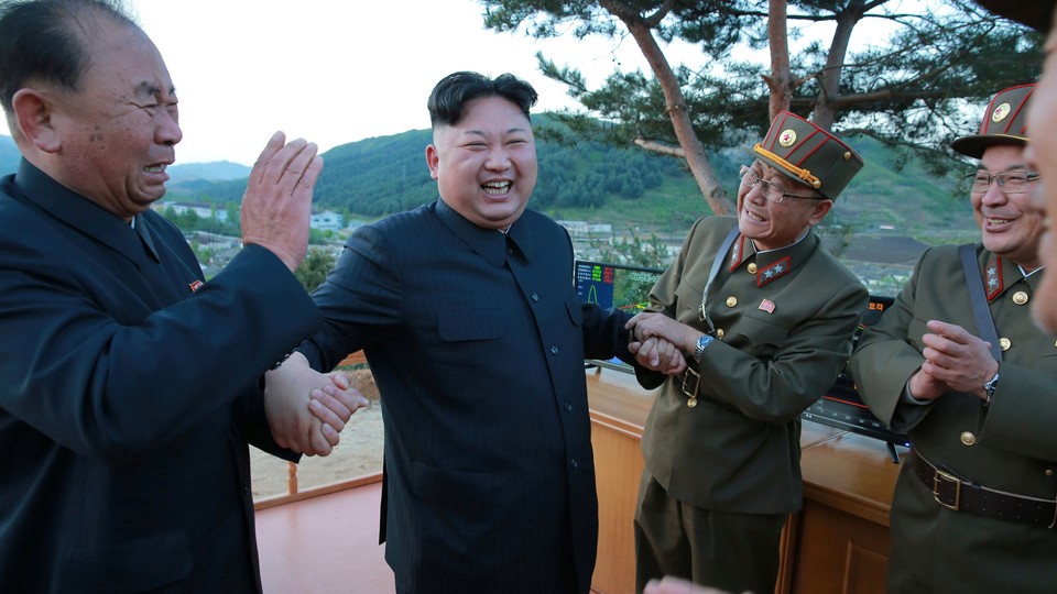 North Korean leader Kim Jong Un reacts with scientists and engineers.