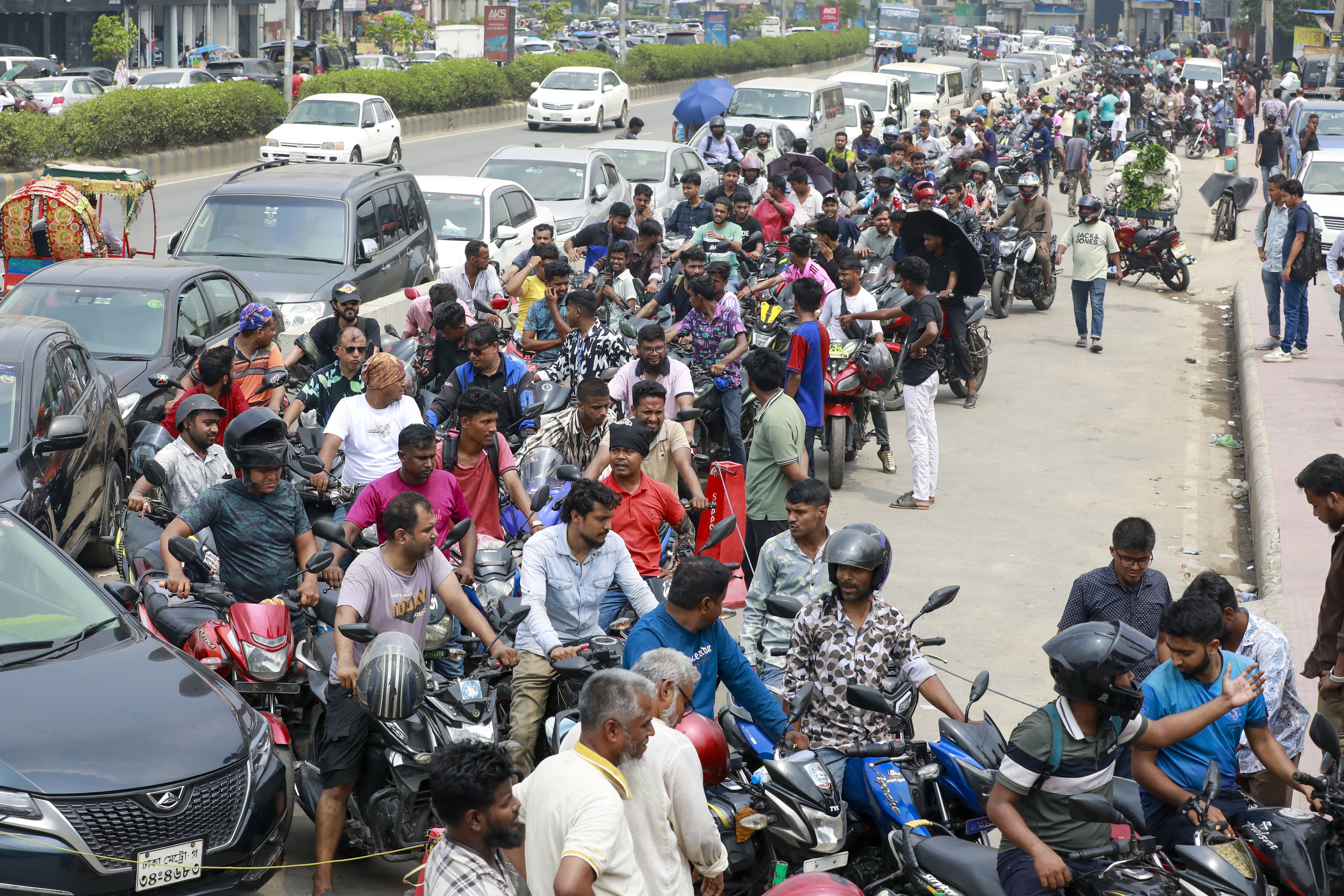 People on scooters wait in a long line to buy fuel.