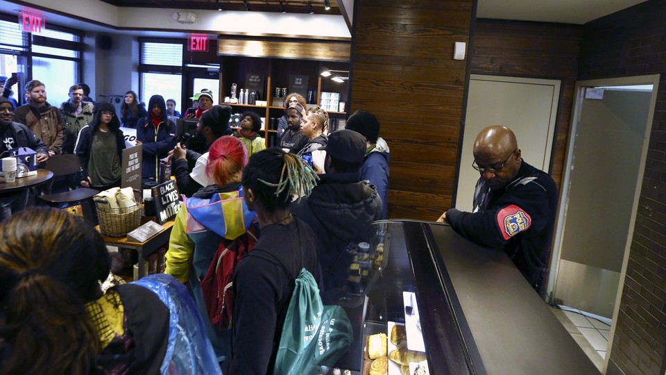 Demonstrators gather in a Starbucks as a police officer watches them.